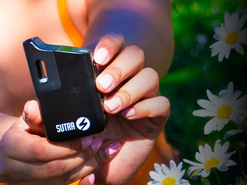 Woman holding Sutra Mini near spring flowers